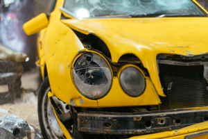 a yellow car damaged from a car accident and the driver will talk to personal injury attorneys