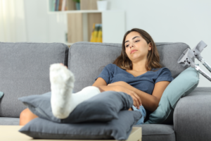 woman on a couch with a cast on her leg wondering who should be held liable for her legal case